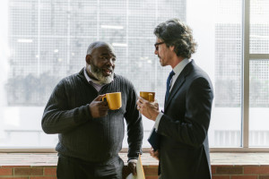 Two Business Men Drinking Coffee By Window