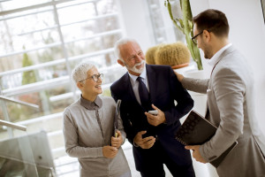 Young businessman with senior clients standing in office