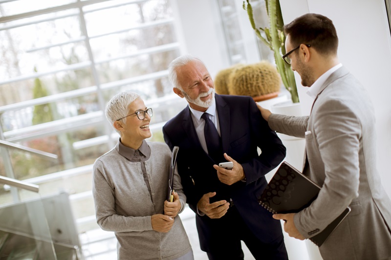 Young businessman with senior clients standing in office