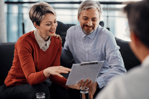 man and woman reviewing document on clipboard happyily with professional (1)
